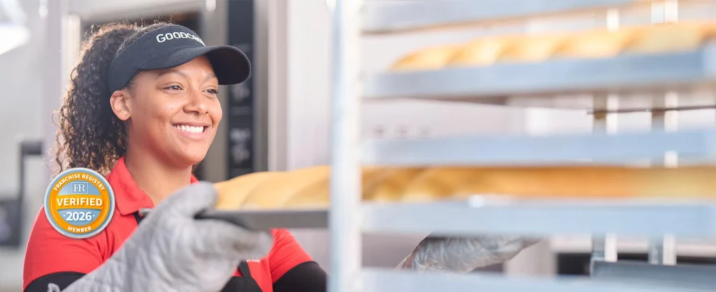Goodcents employee putting freshly baked rolls on cooling rack with badge